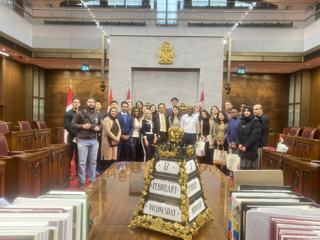 A group photograph in a parliamentary meeting room.