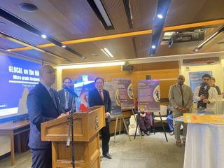 A speaker addressing guests beside project posters.
